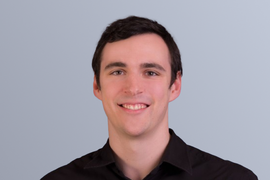 Smiling man wearing a black shirt against a light gray background.